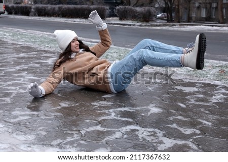 Young woman fallen on slippery icy pavement outdoors Royalty-Free Stock Photo #2117367632
