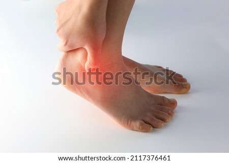 A person holding ankle on Achilles tendon, suffering with pain in red spot area. Sprain ligament or Achilles tendonitis symptoms. Image with red highlights on hurting area, Health care concept Royalty-Free Stock Photo #2117376461