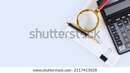 Calculator, pen, magnifying glass and a stack of documents on the auditor's desktop preparing the annual, financial report and balance sheet. The concept of accounting and auditing. copy space. 