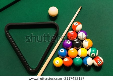 Different billiard balls with cue and rack on green table Royalty-Free Stock Photo #2117432159