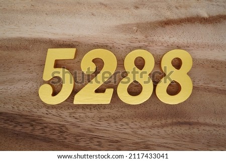 Wooden Arabic numerals 5288 painted in gold on a dark brown and white patterned plank background.
