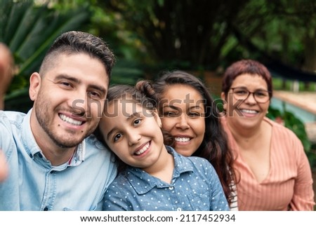 brazilian family generations looking at camera and smiling for selfie outside in the garden Royalty-Free Stock Photo #2117452934