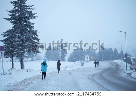 some people are walking along the highway in the winter in the hill plain area
