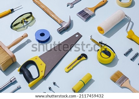 Flat lay still life of a large selection of assorted workshop tools and hardware arranged diagonally over blue Royalty-Free Stock Photo #2117459432