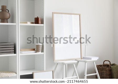 Blank poster on chairs near light wall in room