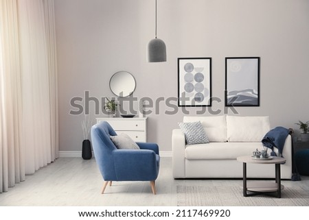 Stylish living room interior with white sofa, armchair and small coffee table Royalty-Free Stock Photo #2117469920
