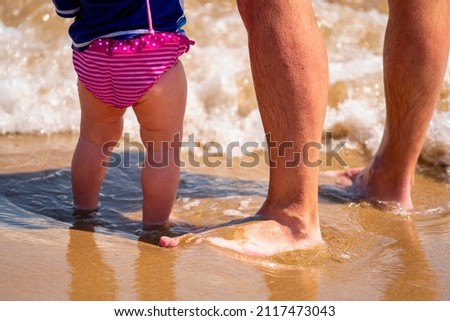 Father and baby feet at the beach sand. Horizontal image.