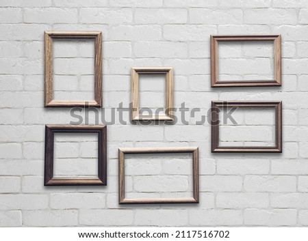 old photo frames on white brick wall
