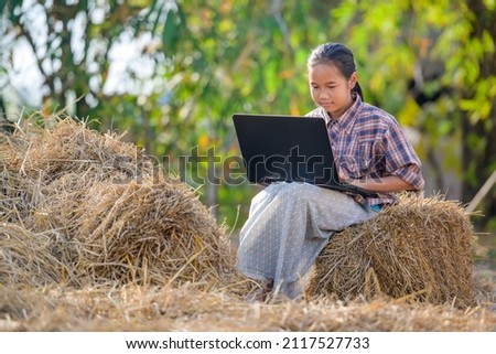 A poor Asian primary school girl live in rural areas and schools in rural Thailand sitting and watching notebook computer to study and study online using a laptop Royalty-Free Stock Photo #2117527733