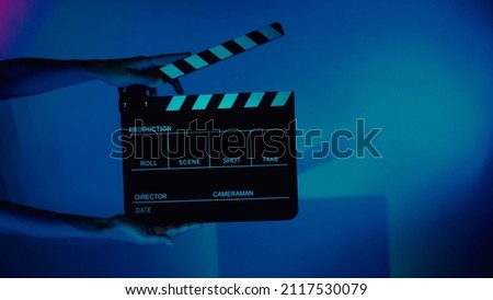 Blurry images of movie slate or clapper board. Hand holds empty film making clapperboard on color background in studio for film movie shooting or recording. Film slate for Youtuber video production. Royalty-Free Stock Photo #2117530079