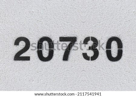 Black Number 20730 on the white wall. Spray paint.two thousand seven hundred thirtytwo thousand seven hundred thirty