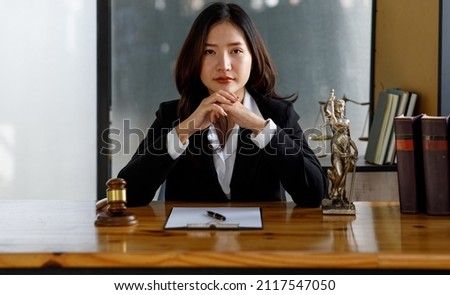 A Female lawyer in suit at the workplace with laptop, gavel and femida in office, Lawyer office Statue of Justice with scales and lawyer working on a laptop. Legal law, advice and justice concept.