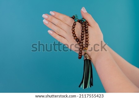 Praying woman on blue background, meditating, reading mantras, directs thoughts, requests or gratitude to universe. Isolated. Spirituality, religion, God concept.