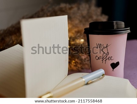 Cup of coffee and open notebook on table. 