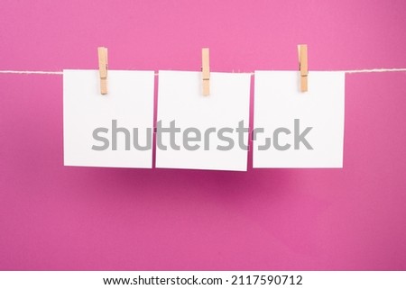 Empty white sheets of paper in a row hanging on a string, copy space for pictures and text, message communication and marketing background, pink color