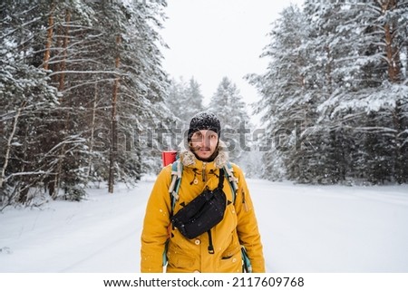 portrait of traveler with belt bag and and bright backpack. Winter equipment.Snowy forest and rocks. Climbing the mountain in winter. Survival in the wild. High quality photo