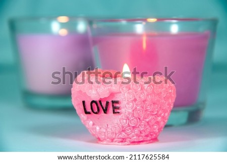 Focus on the pink candle. Romantic background. Candle holders, fire and romance. Background in blue tones.