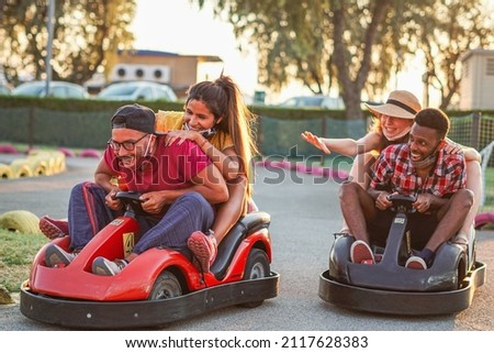 Group of multiracial friends having fun with go kart  - Young people with face mask on smiling and cheerful at mini car racing - Couples outside in double date - New lifestyle Royalty-Free Stock Photo #2117628383