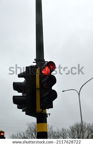 Looking up. Focus on Stoplight is red with a overcast sky in background