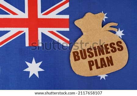 On the flag of Australia lies a cardboard figure of a money bag with the inscription - BUSINESS PLAN