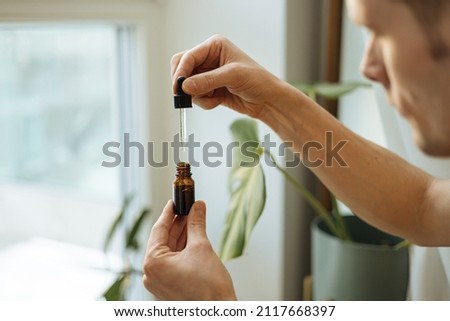 Vitamins and supplements. Hand holding pipette of Hemp oil. Close up man uses CBD oil. Medical cannabis. Healthy lifestyle and daily dose of tincture Royalty-Free Stock Photo #2117668397