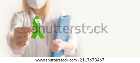 World bipolar day. Doctor in white coat holds green ribbon. Mental health awareness day, Depression, Cerebral palsy. World kidney day. banner. copy space. Royalty-Free Stock Photo #2117673467