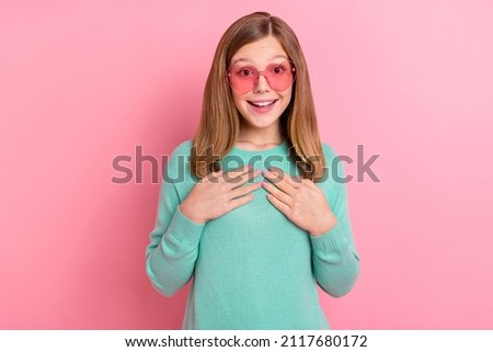 Photo of excited school girl dressed teal pullover heart eyewear arms chest isolated pink color background