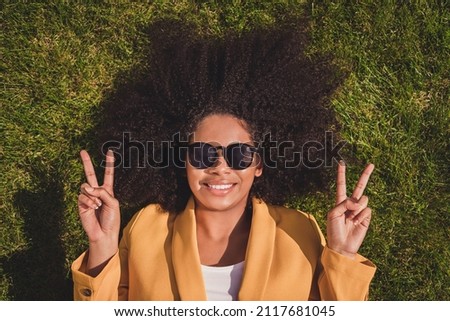 Top above high angle view portrait of attractive cheerful girl lying on grass showing double v-sign good mood weather outdoors