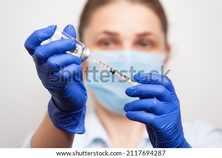 a nurse in medical gloves dialing a vaccine or medicine for injection into the syringe