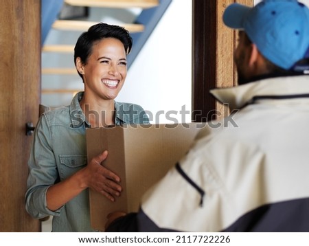 It got here so fast. Shot of a smiling young woman standing at her front door receiving a package from a courier. Royalty-Free Stock Photo #2117722226