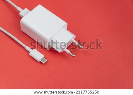 Charger and USB cable type C over red background Royalty-Free Stock Photo #2117755250