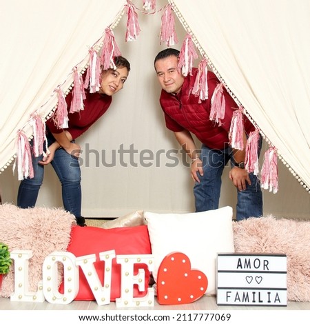 Latin Hispanic adult couple demonstrate love under a teepee with a sign that says "love and family" very happy they celebrate Valentine's Day of Love and Friendship in February
