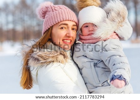 smiling woman hugs little girl in winter