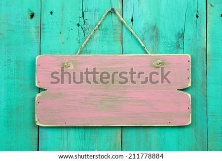 Distressed pink blank sign hanging on antique green rustic wooden fence