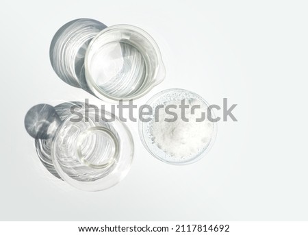Closeup chemical ingredient on white laboratory table. Di-Ammonium Prosphate in Chemical Watch Glass place next to beaker with alcohol and Erlenmeyer flask. Top View Royalty-Free Stock Photo #2117814692