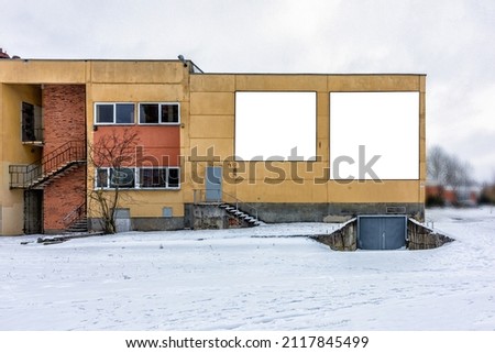 Two empty square stands for advertising on the wall of an old building in winter
