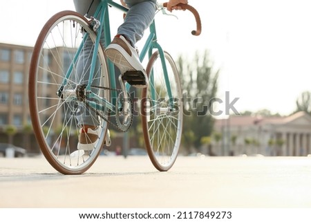 Young man riding bicycle on city square, closeup Royalty-Free Stock Photo #2117849273