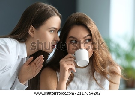 Female colleagues gossiping in office Royalty-Free Stock Photo #2117864282