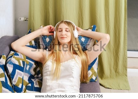 Smart woman listens to a podcast lying on the couch with her eyes closed at home