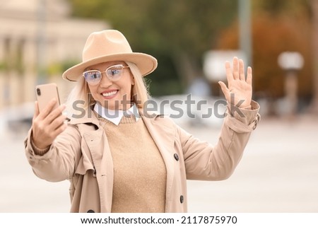 Fashionable mature woman taking selfie on city street