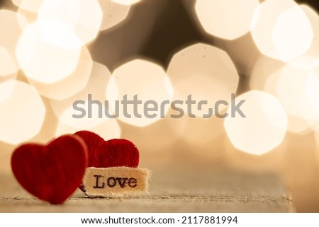 Valentine's Day greetings concept. Little red wooden heart and text Love close up, bokeh on the background. Valentines greeting card.