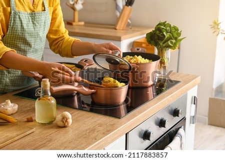 Woman in apron preparing corn cobs in kitchen Royalty-Free Stock Photo #2117883857