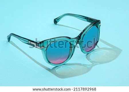 Fashion female Sunglasses in beautiful sunlight on blue background. Royalty-Free Stock Photo #2117892968