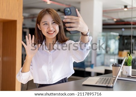 Beautiful Asian woman holding a cell phone to take a selfie, she takes a photo of herself on social media to get likes from followers. The idea of taking pictures for social media.