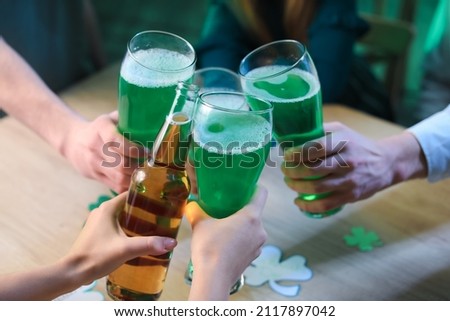 Friends with glasses of beer celebrating St. Patrick's Day in pub, closeup