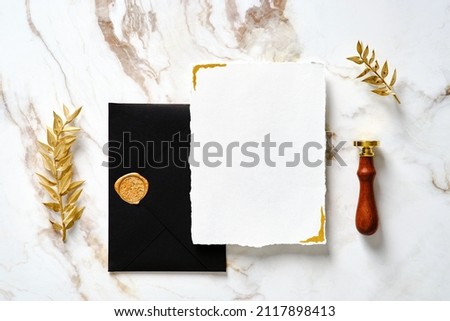 Flat lay luxury wedding invitation card mockup, black envelope, gold wax seal stamp, golden leaves. Elegant wedding stationery set on marble gold table. Royalty-Free Stock Photo #2117898413