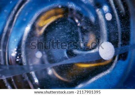 Geometric abstraction of ice figure with cracks and air bubbles. Winter colored texture. Blurred blue and yellow spiral. Selective focus.