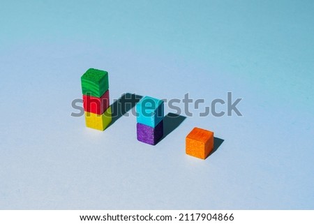 Wooden colorful cubes with dark shadow on blue background. Geometric shapes composition.