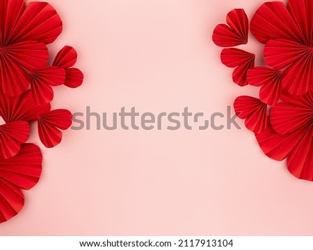 Valentines day festive background in asian style - red paper hearts of folded fans as sideways border on gentle pastel pink color backdrop, top view, copy space.