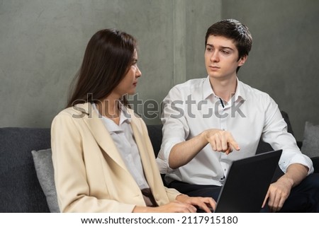 Young caucasian businessman and businesswoman serious look at together, working with computer together, man point to laptop. Young man and woman work business in home office and copy space background